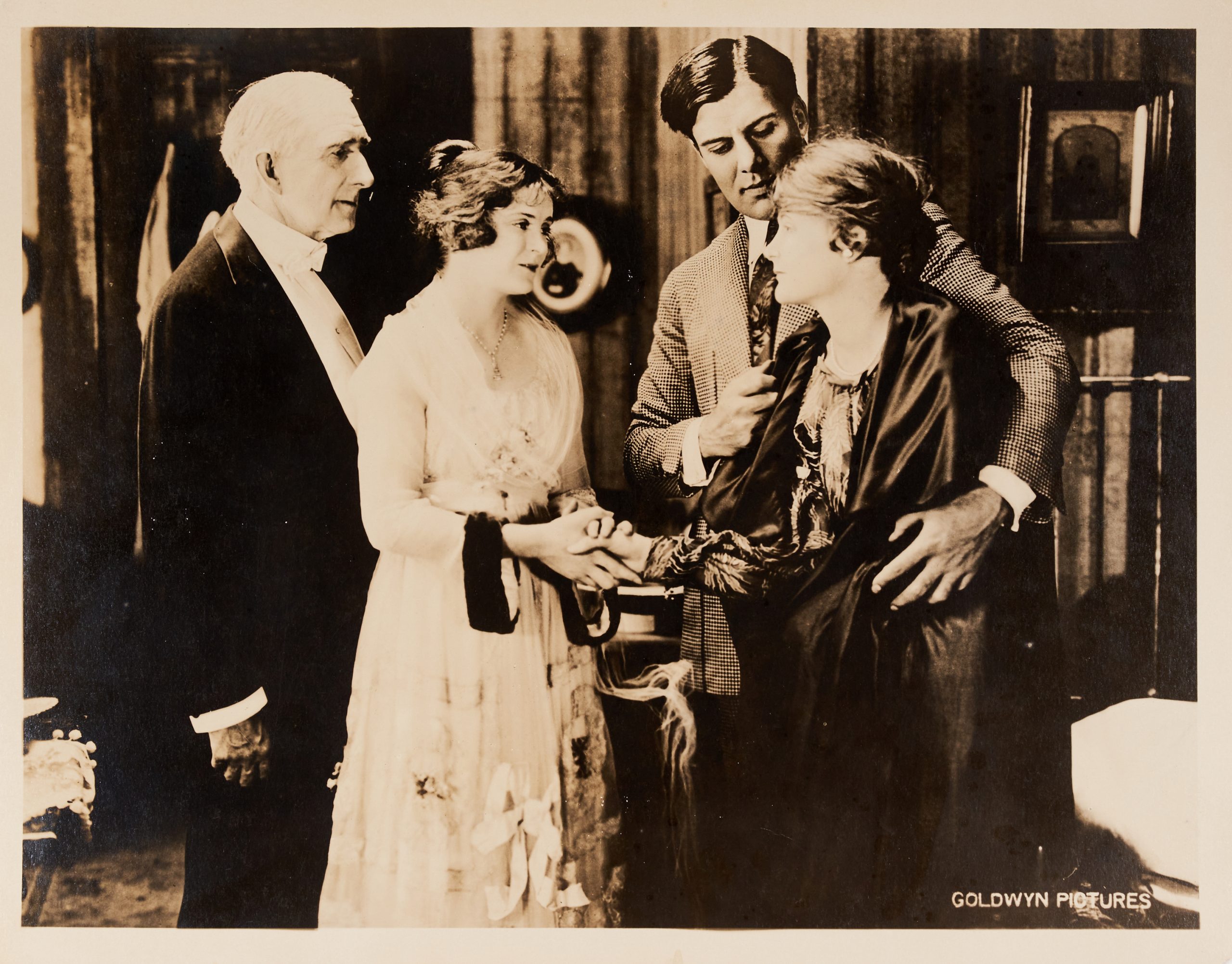 A lobby card showing a man and a couple comforting an older woman.