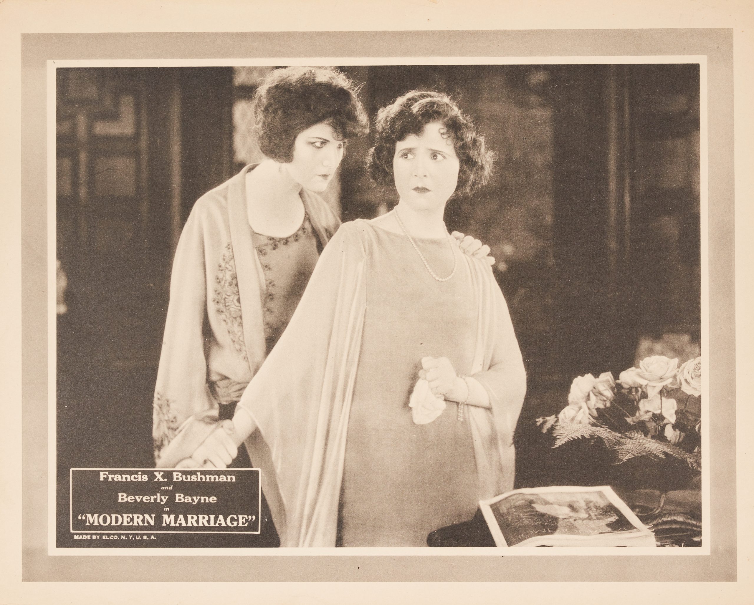 A lobby card with a woman looking upset while another woman clutches and gazes at her menacingly.