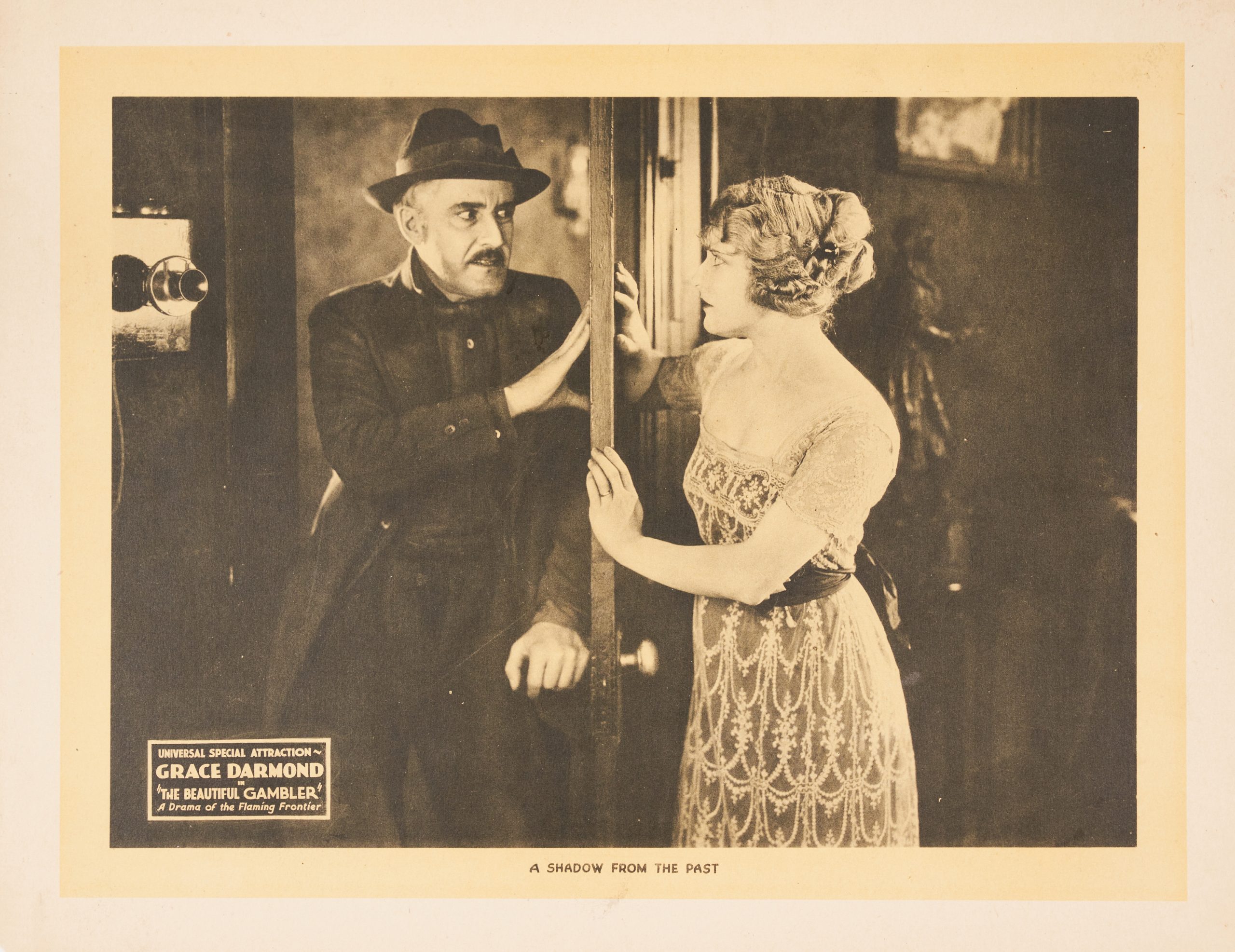 A black-and-white lobby card showing a man and woman on opposite sides of a half open door.