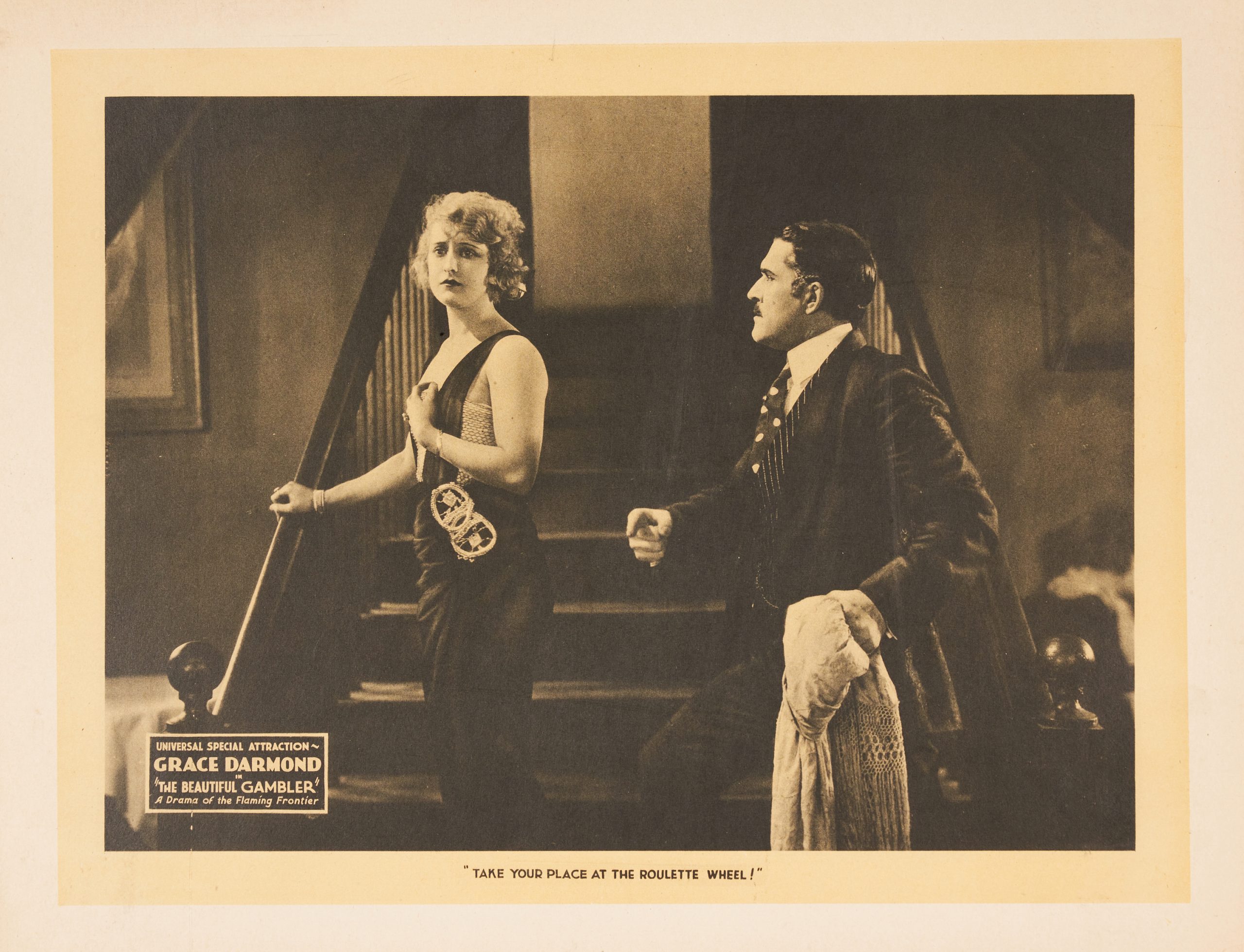 A black-and-white lobby card featuring an elegantly dressed woman approached by a man on a staircase.