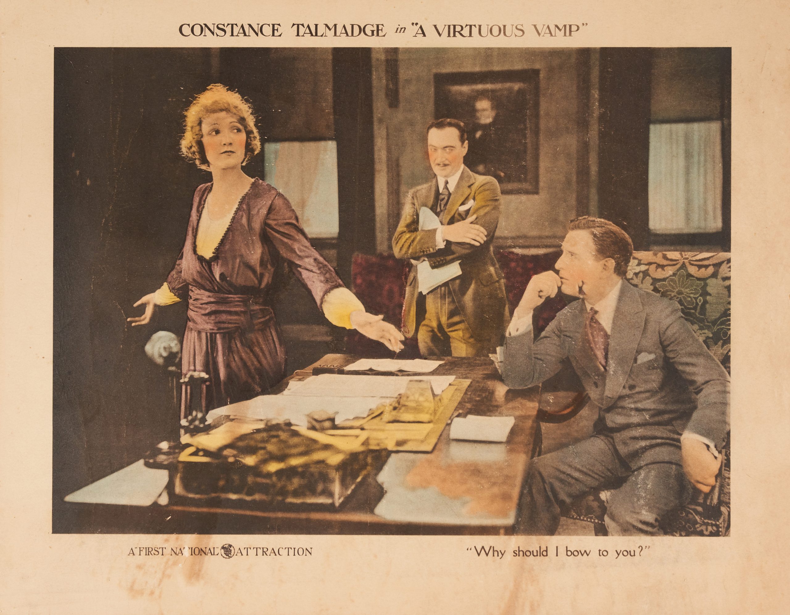 A colored-in lobby card showing a conversation in an office between two men and a defiant woman.