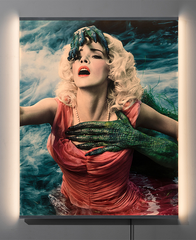 A mixed-media artwork of a frightened woman in water with reptilian hands pulling her in.