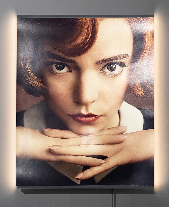 A mixed-media artwork depicting a woman gazing intensely forward and resting her head on her hands.