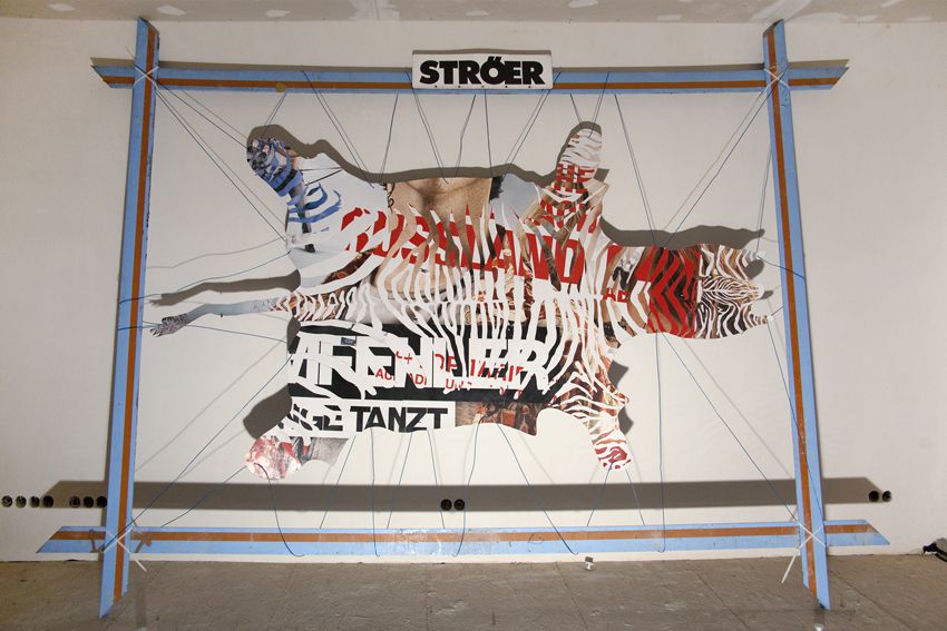 A collaged pelt of a sprawled out animal hung up by string.