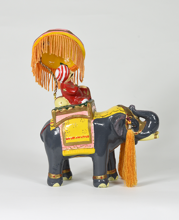 A figurine of a mustachioed figure wearing a turban riding an elephant.