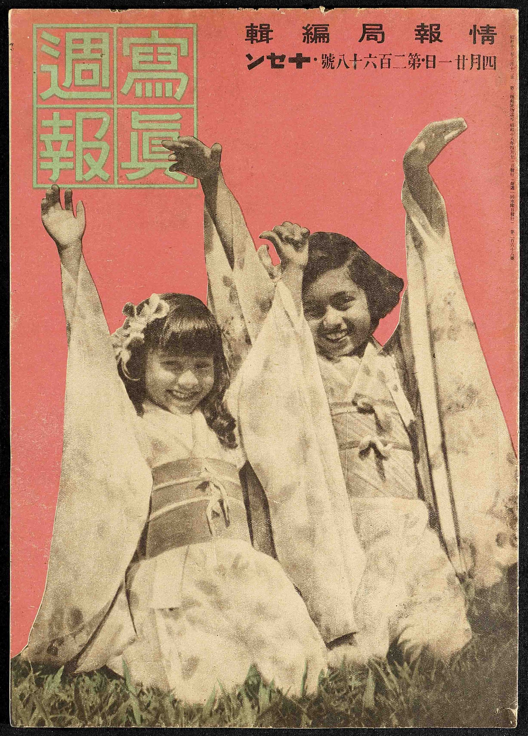 A magazine cover of two young girls sitting on grass with their arms held up wearing dresses.