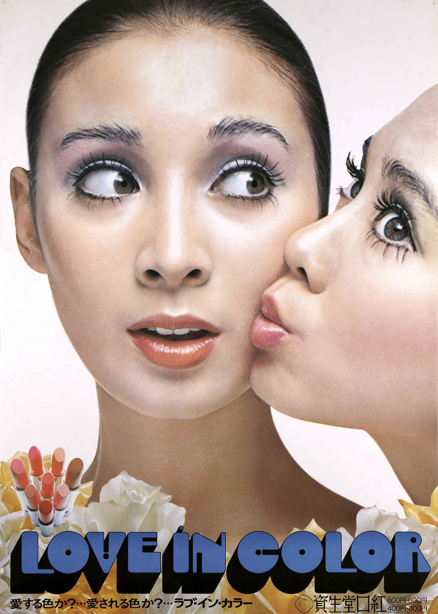A photographic advertisement of two models's faces. One model kisses the other model's cheek.